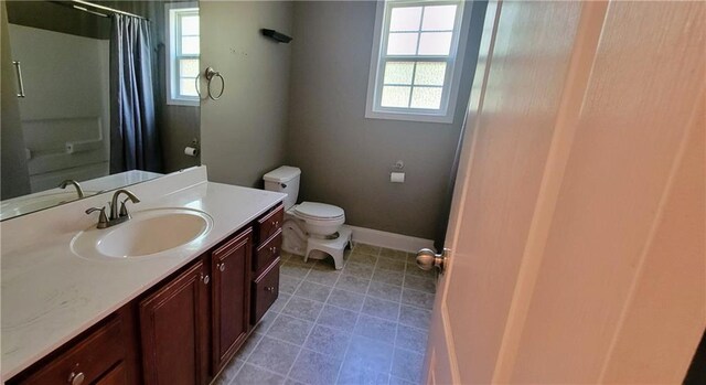 bathroom with vanity, tile patterned flooring, toilet, and walk in shower