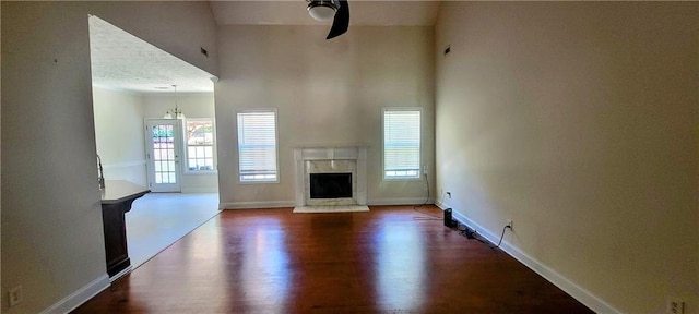 unfurnished living room featuring wood-type flooring, plenty of natural light, and a high end fireplace