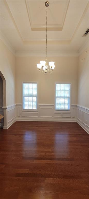 unfurnished room featuring ornamental molding, an inviting chandelier, dark hardwood / wood-style flooring, and a tray ceiling