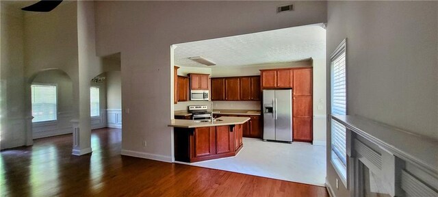 kitchen with appliances with stainless steel finishes, dark hardwood / wood-style floors, a center island with sink, and plenty of natural light