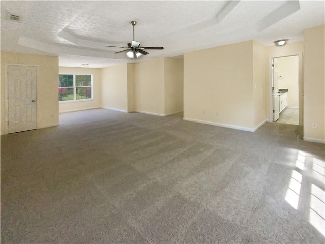 spare room featuring visible vents, a raised ceiling, baseboards, ceiling fan, and carpet