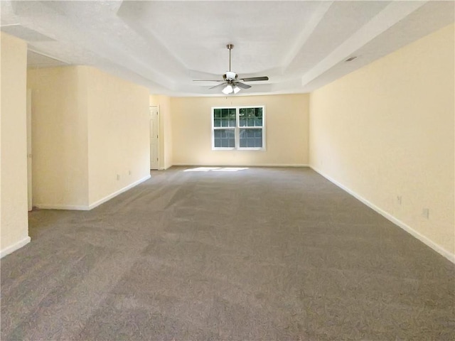 unfurnished room with a ceiling fan, a raised ceiling, carpet flooring, and baseboards