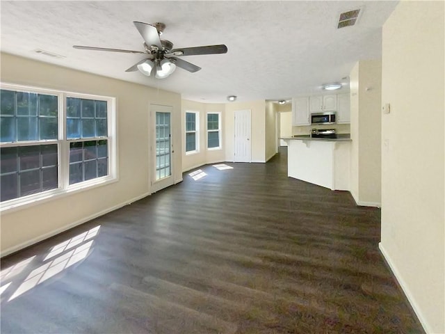 unfurnished living room featuring dark wood-style floors, baseboards, visible vents, and ceiling fan