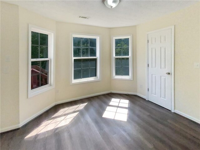 unfurnished room with visible vents, baseboards, and dark wood-type flooring