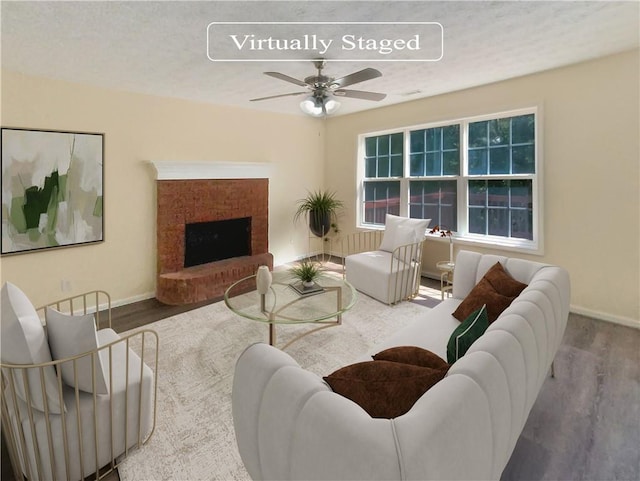 living room with a brick fireplace, wood finished floors, a ceiling fan, and baseboards