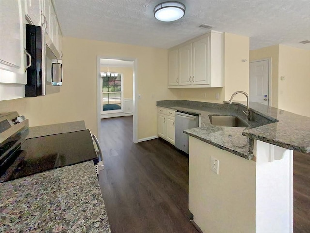 kitchen with stainless steel appliances, a peninsula, a sink, white cabinets, and dark wood finished floors