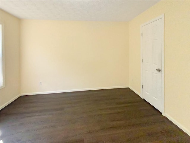 empty room featuring dark wood finished floors and baseboards