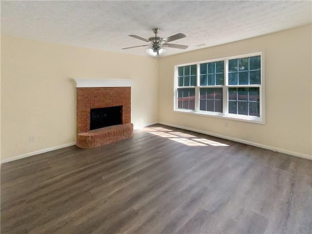 unfurnished living room with dark wood-type flooring, ceiling fan, a fireplace, and a textured ceiling