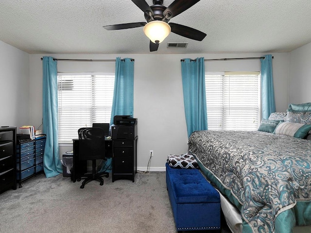 bedroom with a textured ceiling, light colored carpet, and ceiling fan