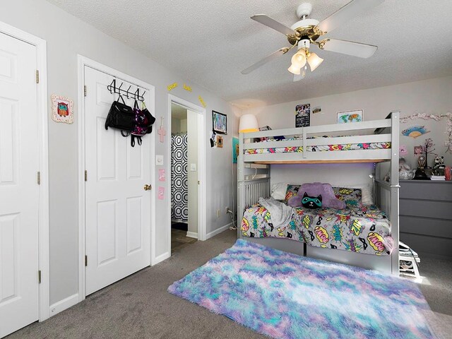 carpeted bedroom featuring ceiling fan and a textured ceiling