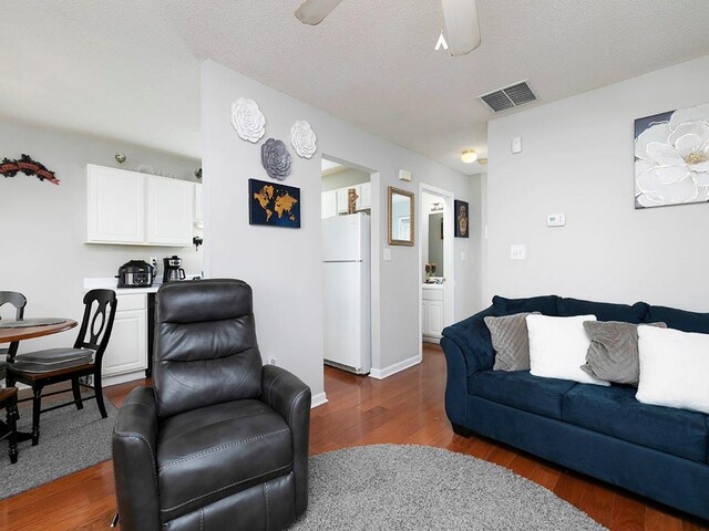 living room featuring ceiling fan, a textured ceiling, and dark hardwood / wood-style floors