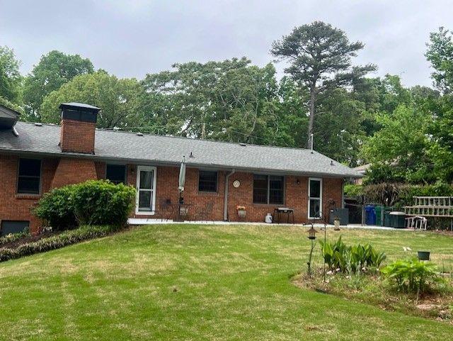 3996 Indian Manor Dr, Stone Mountain, GA 30083 - view of front facade featuring a chimney, brick siding, and a front yard