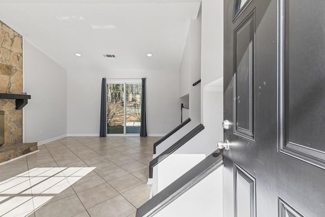 tiled entrance foyer featuring a stone fireplace and vaulted ceiling