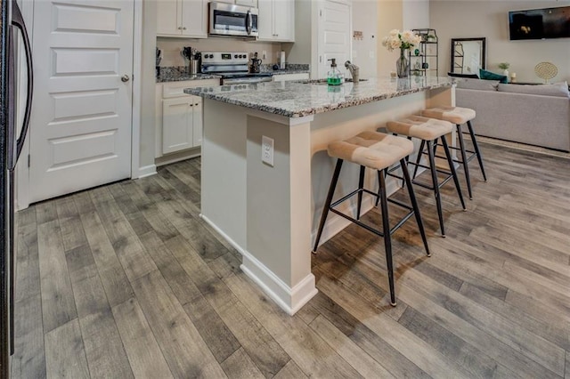 kitchen featuring appliances with stainless steel finishes, a breakfast bar, a sink, and wood finished floors