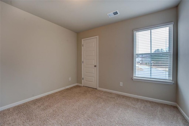 empty room with visible vents, light carpet, and baseboards