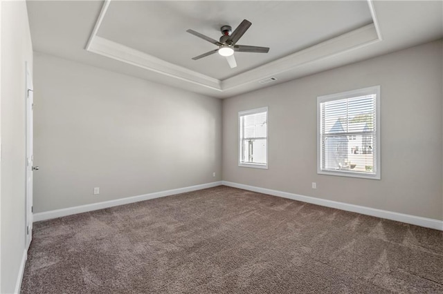 unfurnished room featuring a raised ceiling, ceiling fan, and carpet flooring