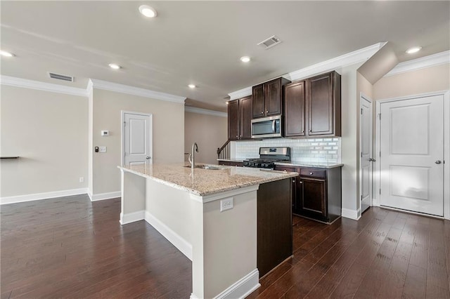 kitchen featuring sink, tasteful backsplash, a center island with sink, ornamental molding, and appliances with stainless steel finishes