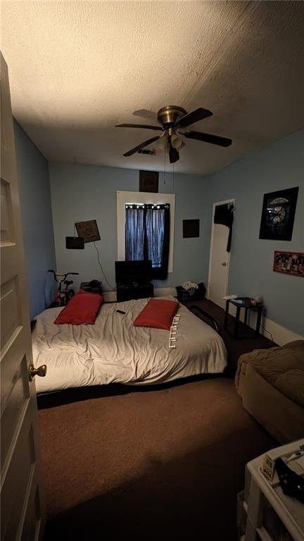 carpeted bedroom featuring ceiling fan and a textured ceiling