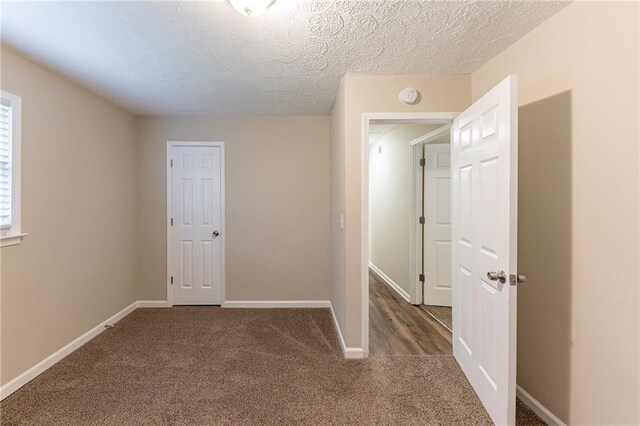 interior space featuring dark colored carpet and a textured ceiling