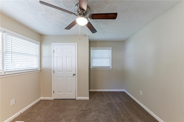 unfurnished bedroom with ceiling fan, a textured ceiling, a closet, and dark carpet