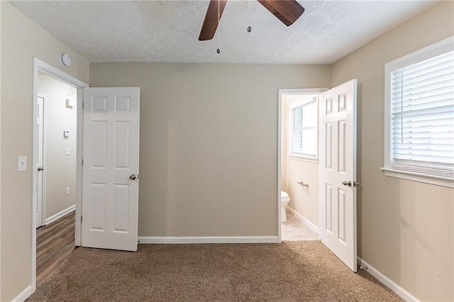 unfurnished bedroom with ceiling fan, a textured ceiling, connected bathroom, and carpet floors