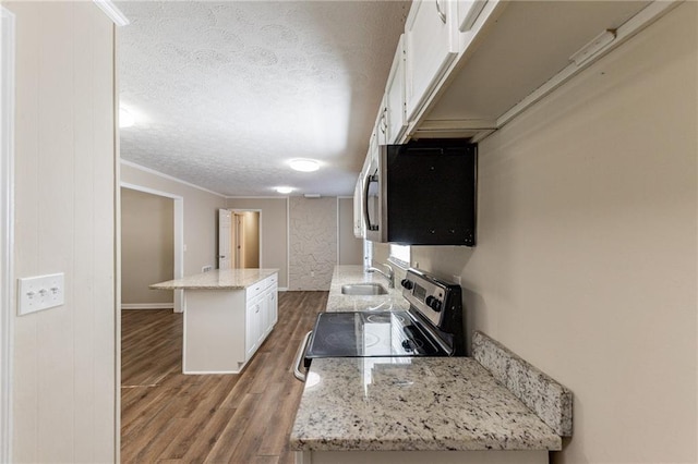 kitchen with white cabinetry, appliances with stainless steel finishes, a textured ceiling, wood-type flooring, and a center island