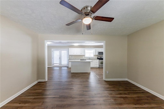 unfurnished living room featuring ceiling fan, dark hardwood / wood-style floors, a textured ceiling, and french doors