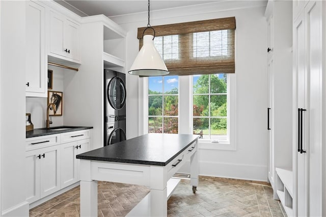 10155 Cedar Ridge Dr, Milton, GA 30004 - kitchen featuring a sink, stacked washer and clothes dryer, dark countertops, baseboards, and white cabinets