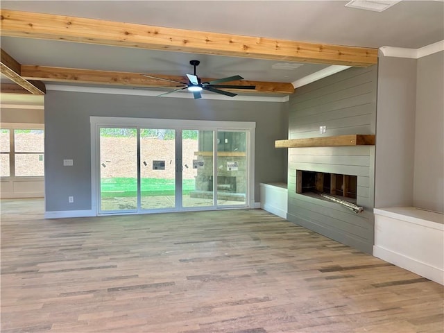 unfurnished living room featuring baseboards, ceiling fan, wood finished floors, beamed ceiling, and a large fireplace