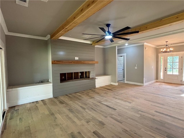unfurnished living room featuring wood finished floors, beam ceiling, visible vents, a fireplace, and crown molding