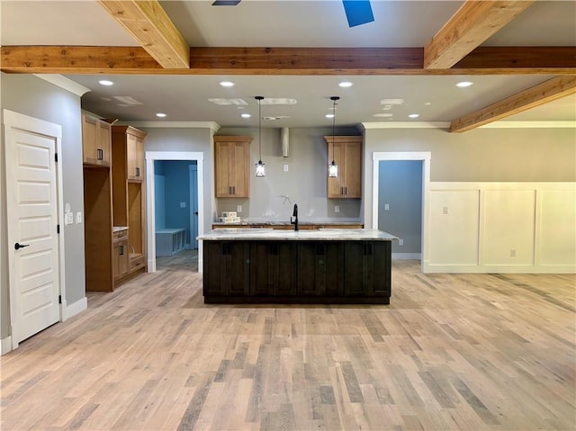 kitchen with light wood-type flooring, beamed ceiling, recessed lighting, and an island with sink