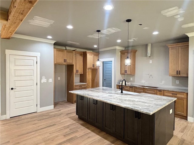 kitchen featuring a sink, crown molding, light wood-type flooring, baseboards, and a spacious island
