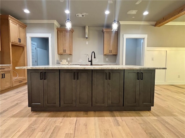 kitchen featuring light wood finished floors, light countertops, an island with sink, and a sink