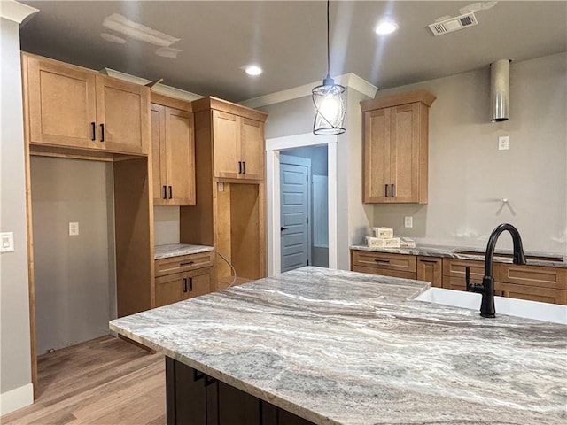 kitchen with recessed lighting, decorative light fixtures, light stone counters, visible vents, and light wood-style floors
