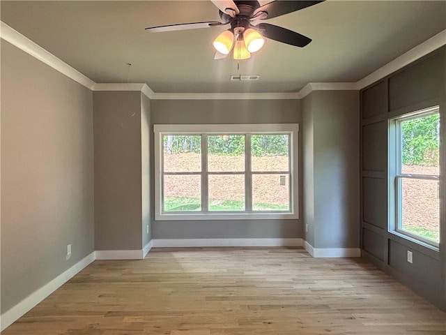 empty room with light wood finished floors, ornamental molding, and baseboards