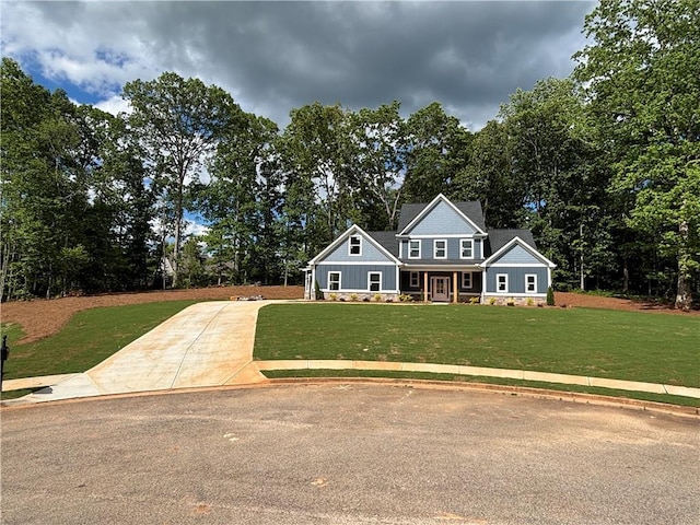 craftsman-style house featuring stone siding, driveway, and a front yard