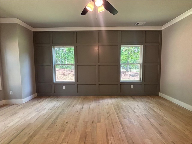 empty room featuring baseboards, a decorative wall, light wood-type flooring, and visible vents