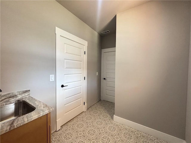 corridor featuring a sink, baseboards, and visible vents