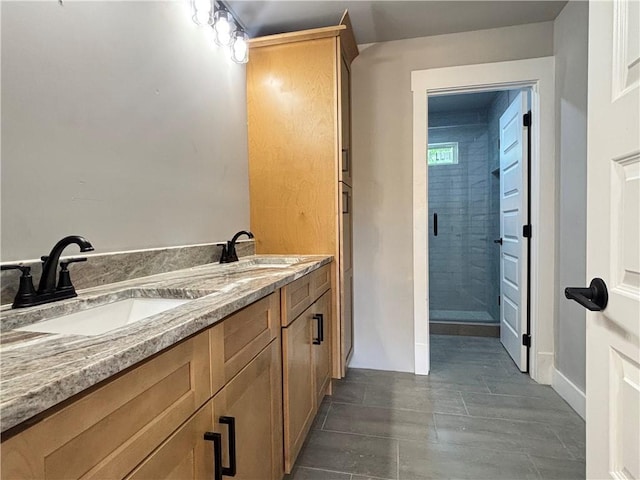 full bath with double vanity, baseboards, a shower stall, and a sink