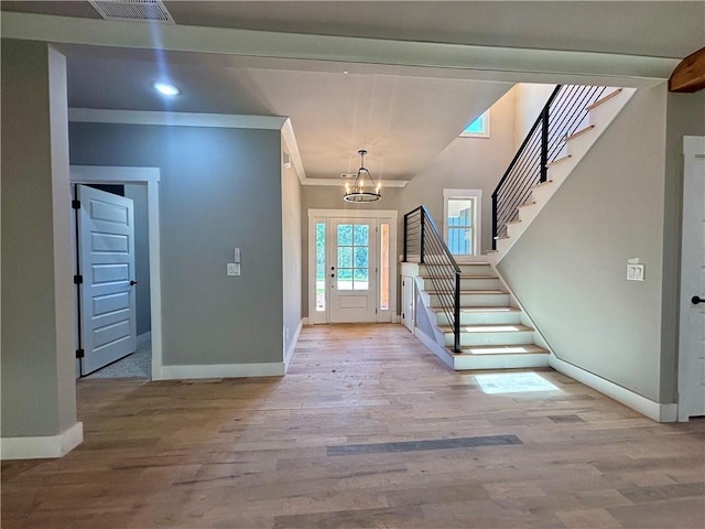 entryway featuring an inviting chandelier, wood finished floors, visible vents, baseboards, and stairs