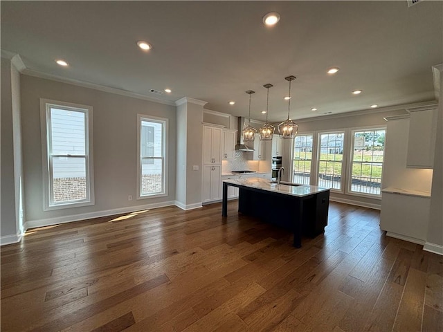 kitchen with sink, crown molding, decorative light fixtures, a center island with sink, and white cabinets