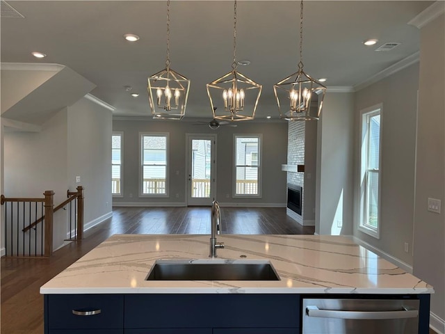 kitchen featuring pendant lighting, white cabinets, wall chimney exhaust hood, and a center island with sink