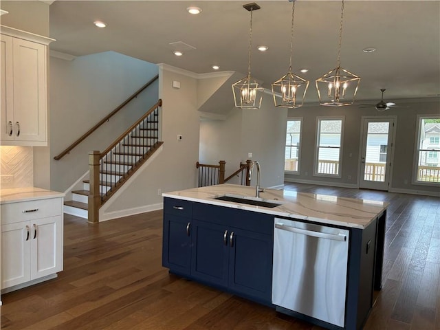 kitchen with hanging light fixtures, an island with sink, sink, and blue cabinets