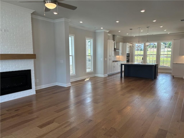 kitchen featuring wall chimney range hood, white cabinetry, stainless steel appliances, ornamental molding, and decorative backsplash