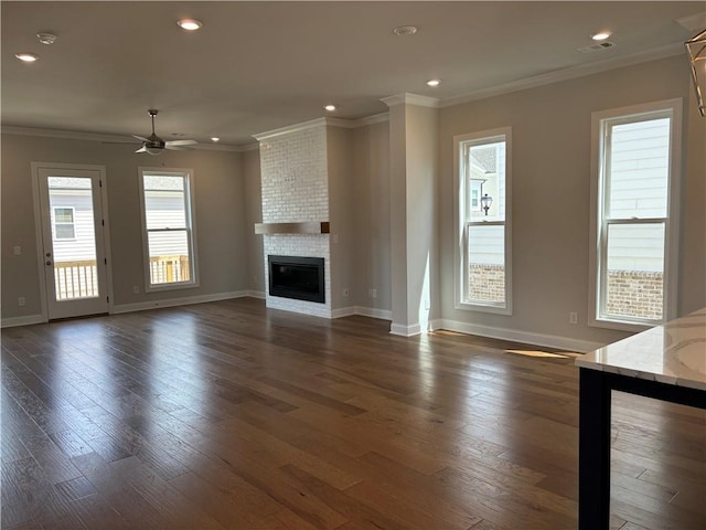 unfurnished living room with a fireplace, dark wood-type flooring, ornamental molding, and ceiling fan