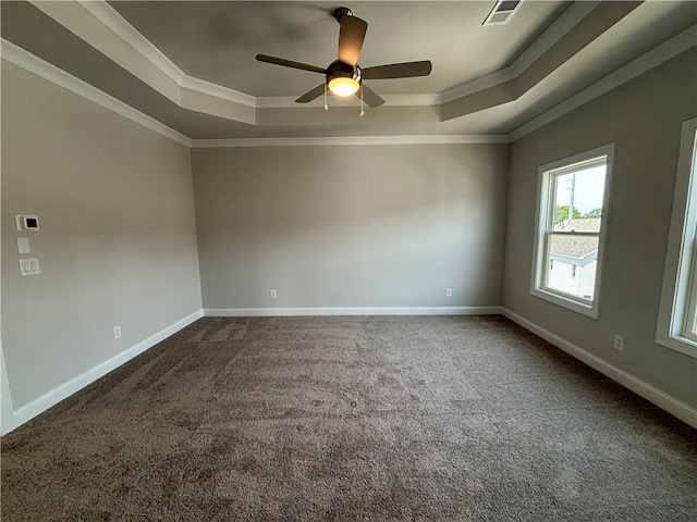 empty room featuring a tray ceiling, ornamental molding, ceiling fan, and carpet