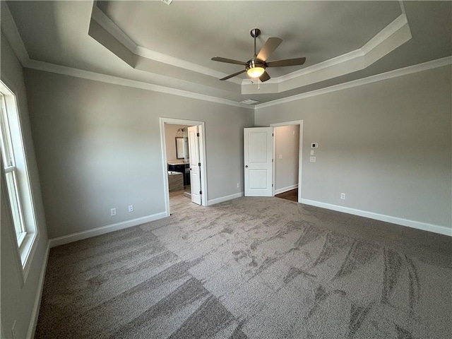 unfurnished bedroom with crown molding, ceiling fan, ensuite bathroom, carpet floors, and a raised ceiling