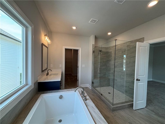 bathroom featuring hardwood / wood-style flooring, plus walk in shower, and vanity