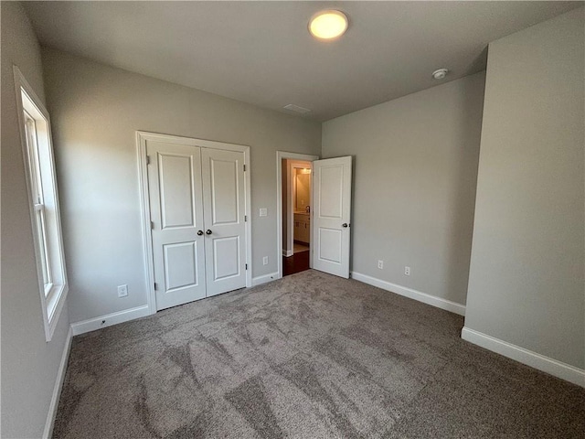 unfurnished bedroom with dark colored carpet and a closet