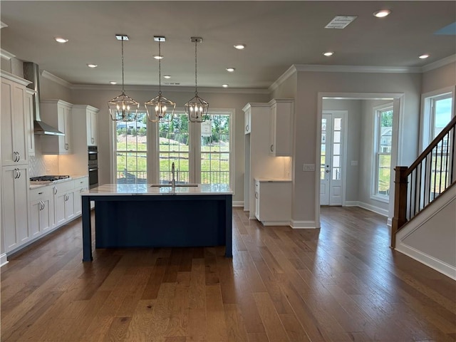 kitchen with sink, white cabinetry, decorative light fixtures, a center island with sink, and appliances with stainless steel finishes